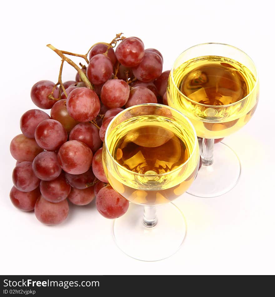 Two glasses of white wine and red grapes on white background