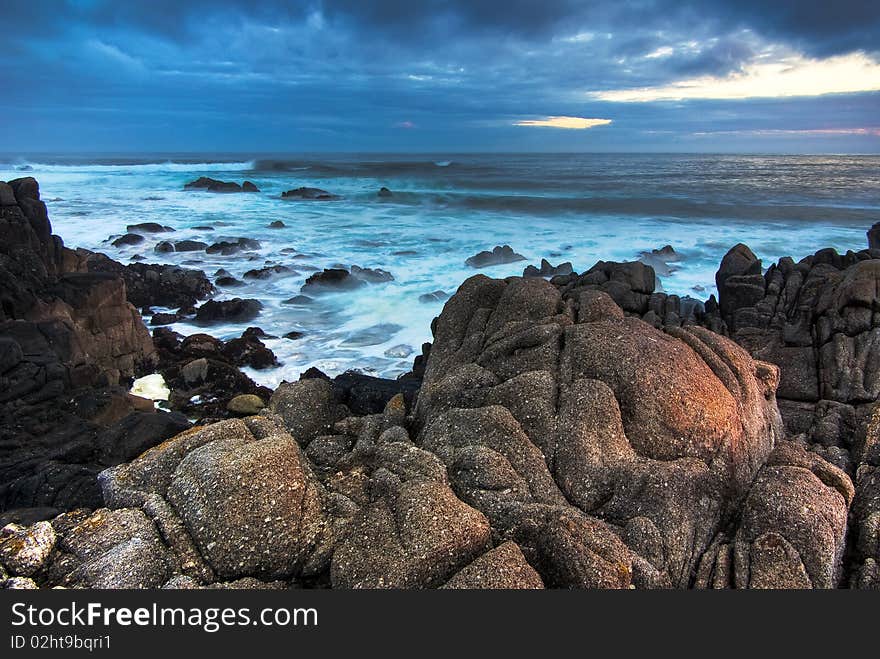 Foreground rocks frame the waves crashing at Monterey at sunrise. Foreground rocks frame the waves crashing at Monterey at sunrise