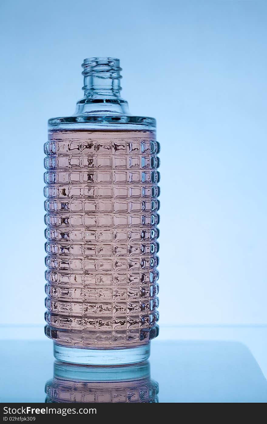 Bottle of perfume isolated over a blue background with reflection. Bottle of perfume isolated over a blue background with reflection.