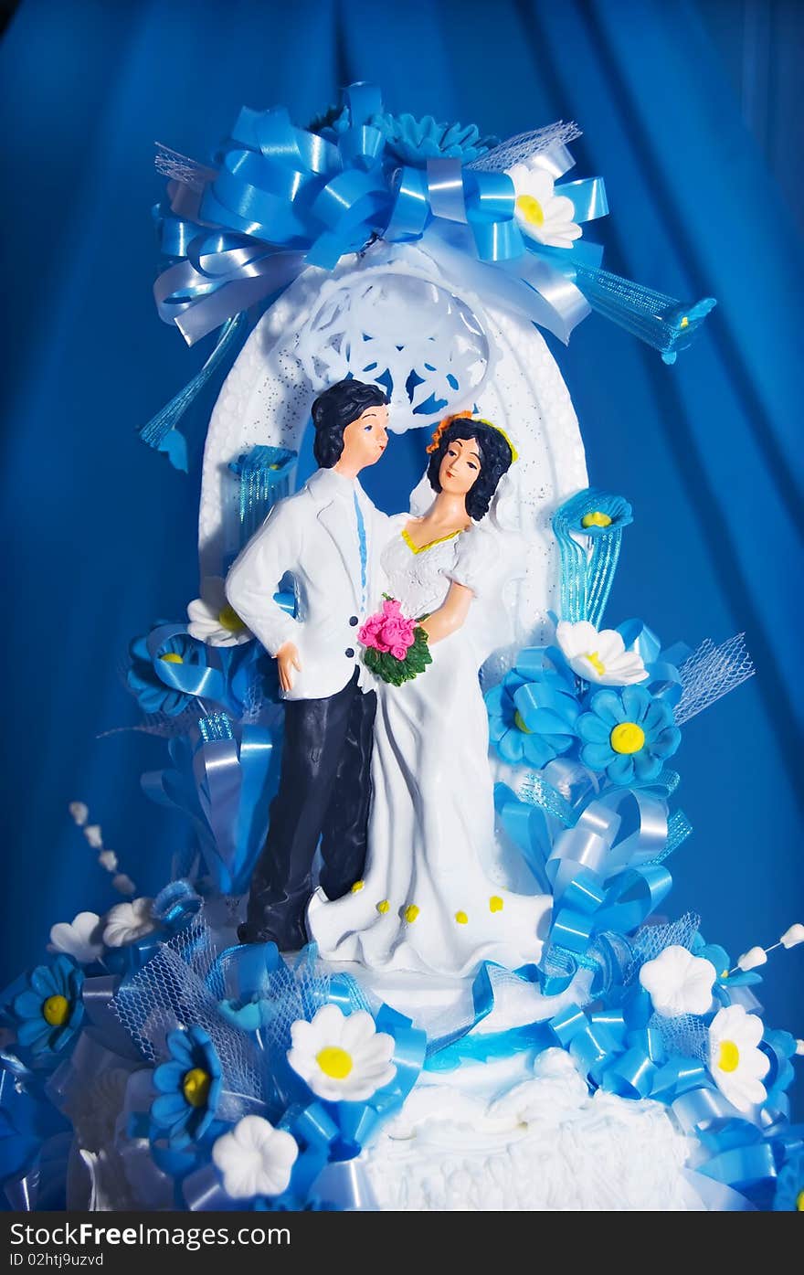 Couple on wedding cake against blue curtain