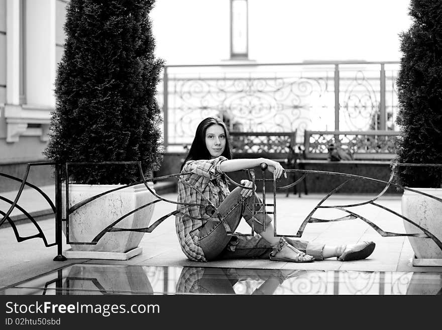 Girl sitting on floor near fence. Girl sitting on floor near fence