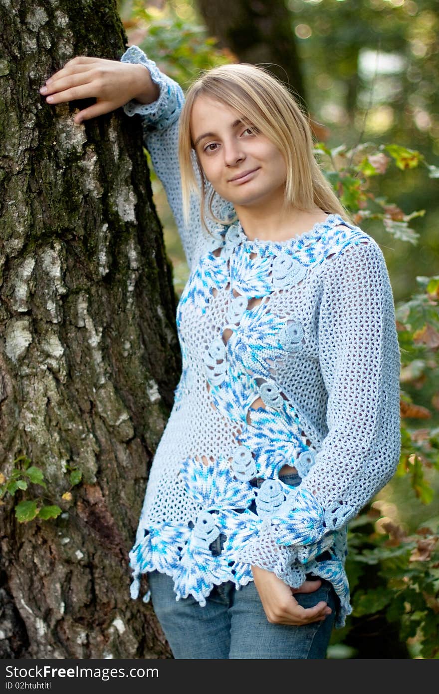 Sunburned girl in blue pullover between two birches