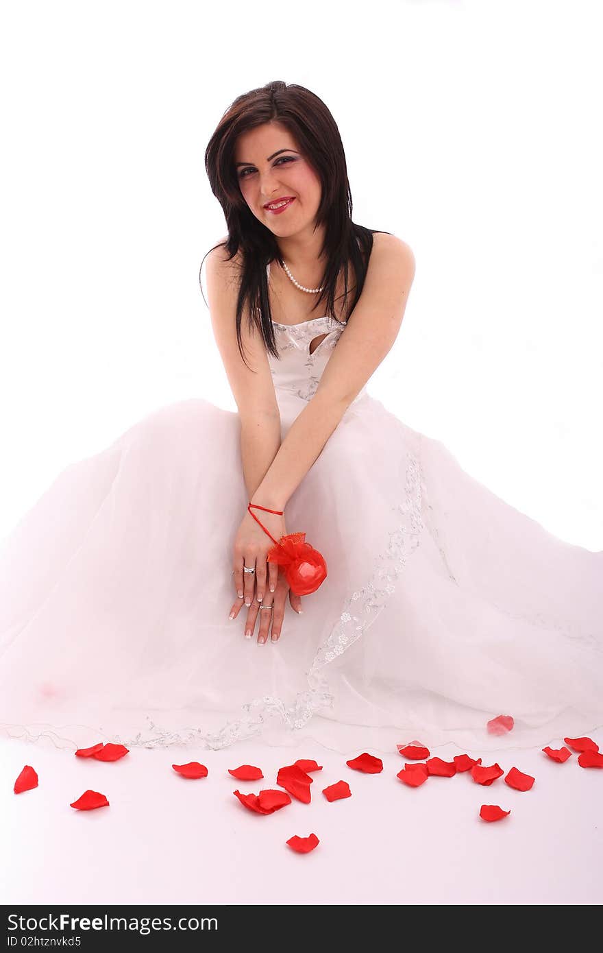 Happy young bride in wedding dress with rose petals on white background