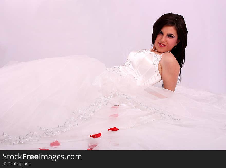 Sitting beauty bride in white dress over white background