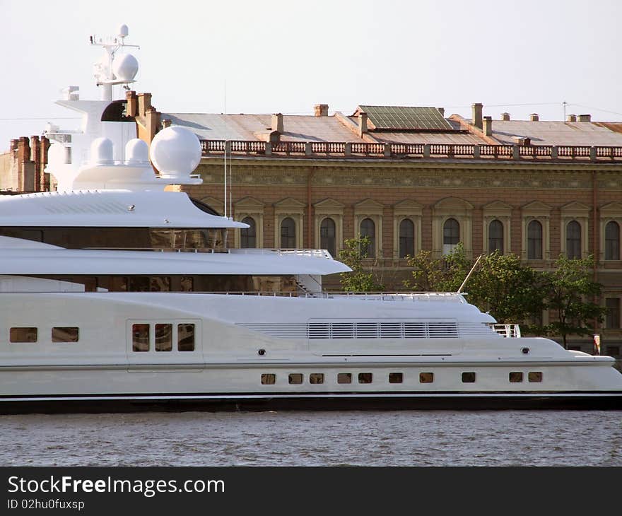 Modern white yacht opposite old building