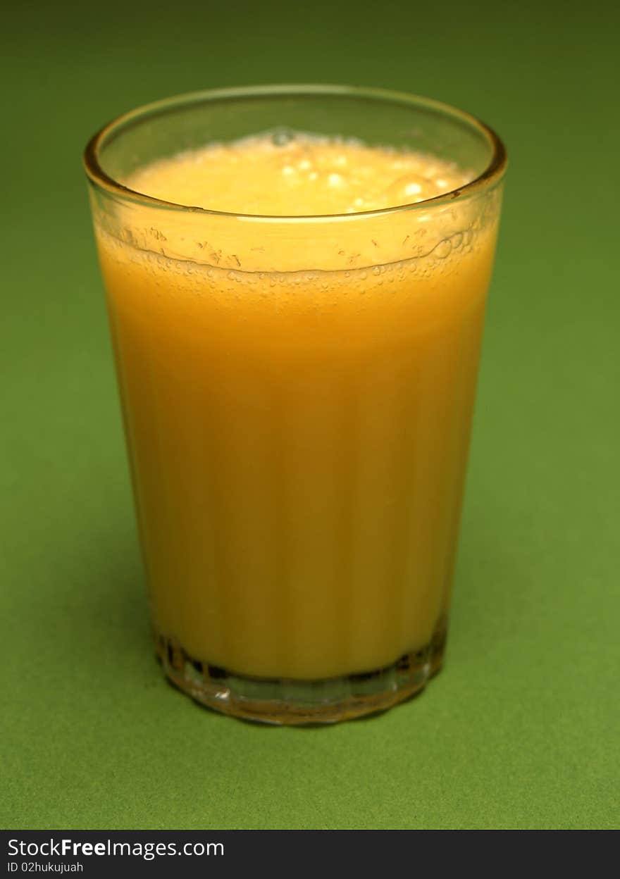 A glass of orange juice on green background. A glass of orange juice on green background