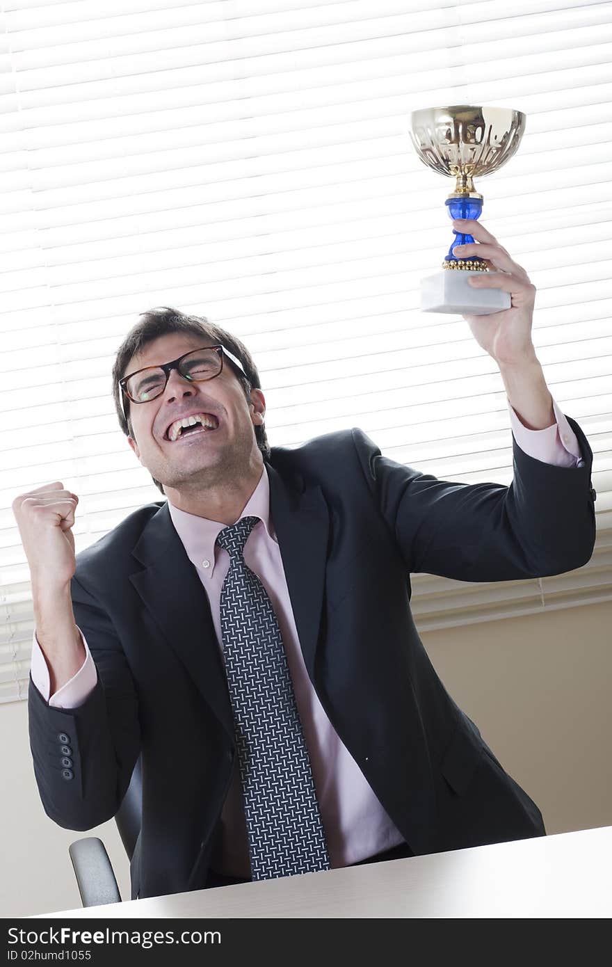 Businessman celebrating raising a cup. Concept: winning the challenge/emerging