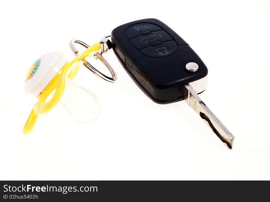 A yellow pacifier attached to a black car key against a white background.