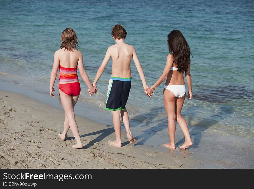 Three Teenagers holding hands enjoying a walk along the shoreline of beautiful Miami Beach. Three Teenagers holding hands enjoying a walk along the shoreline of beautiful Miami Beach.