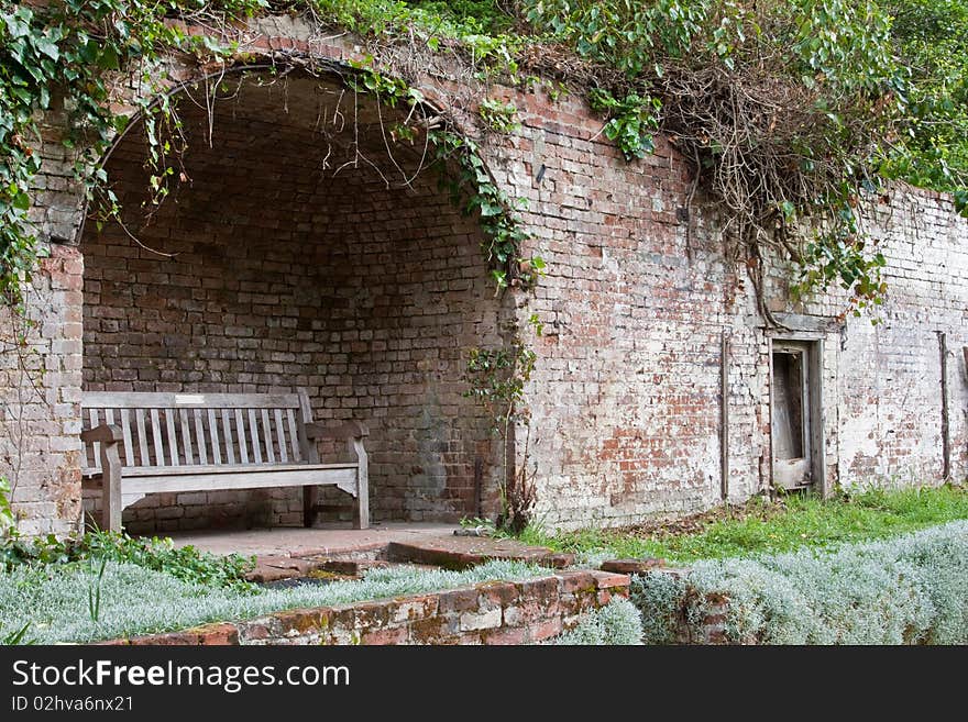 A garden bench in a secluded shelter set into a brick wall. A garden bench in a secluded shelter set into a brick wall