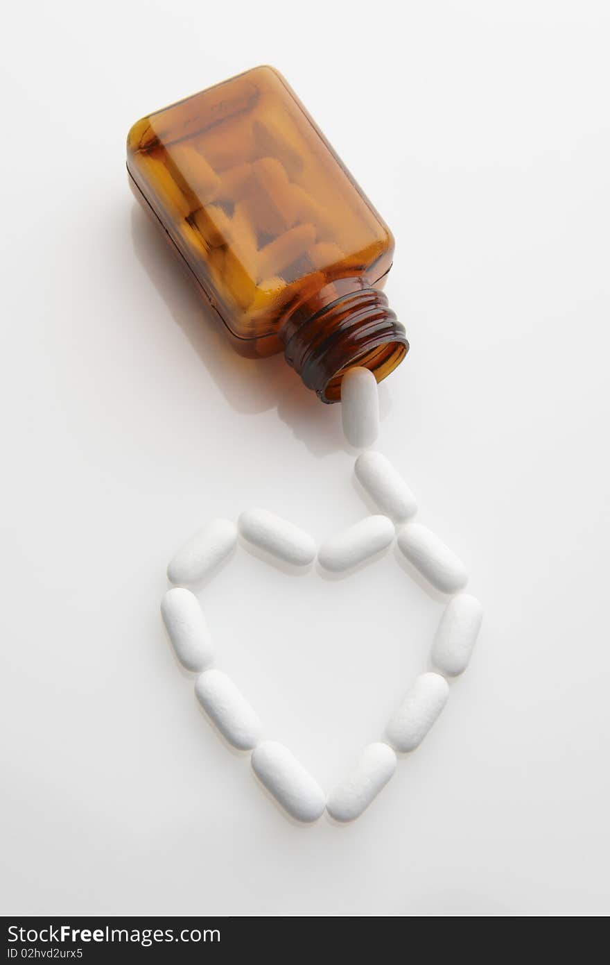 Tablets coming out of bottle and forming shape of a heart. Tablets coming out of bottle and forming shape of a heart