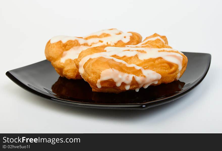 Two pastries filled with custard on black plate on white background. Two pastries filled with custard on black plate on white background