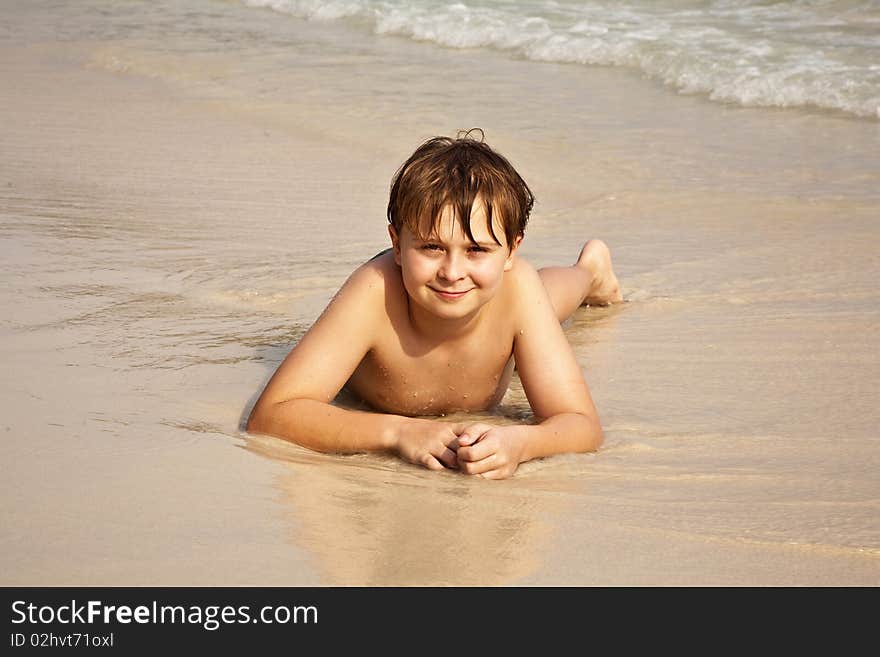 Boy is y lying at the beach and enjoying the warmness of the water and looking self confident and happy. Boy is y lying at the beach and enjoying the warmness of the water and looking self confident and happy