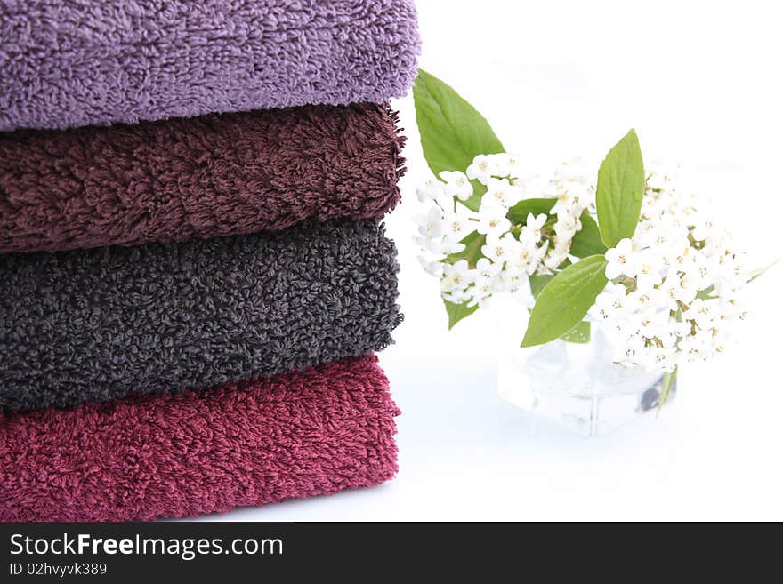 Stack of towels of cotton terry and small vase of white lilac