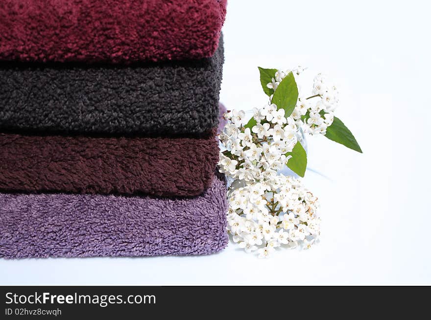 Stack of towels of cotton terry and small vase of white lilac