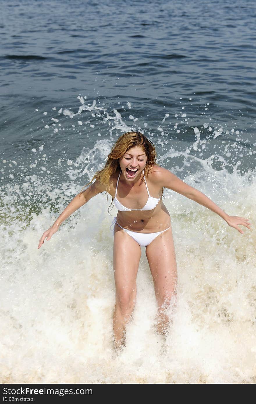 Summer vacation fun: young woman being splashed by a wave