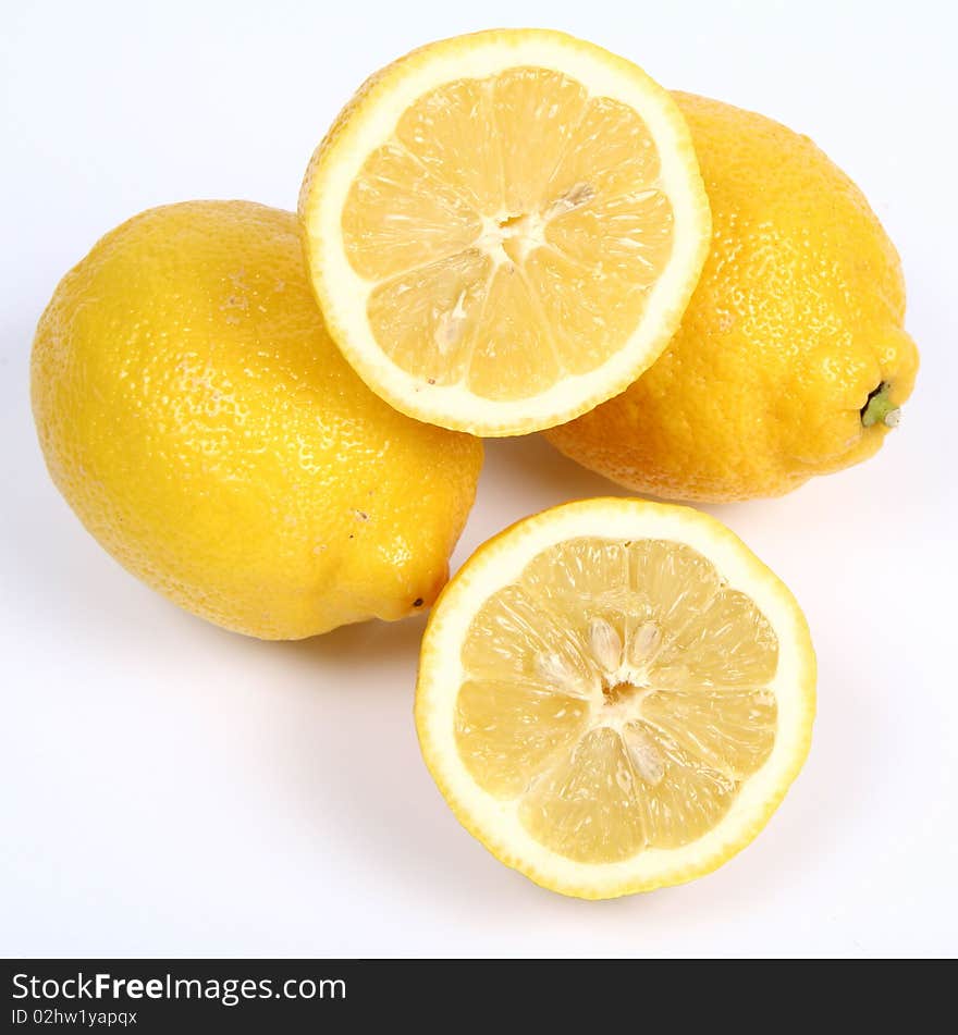 Three lemons, one cut in half, on white background