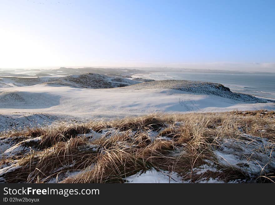 Snow covered links golf course in ireland in winter with sea background. Snow covered links golf course in ireland in winter with sea background