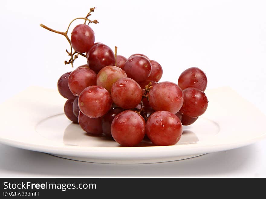 Red grapes on a plate on white background