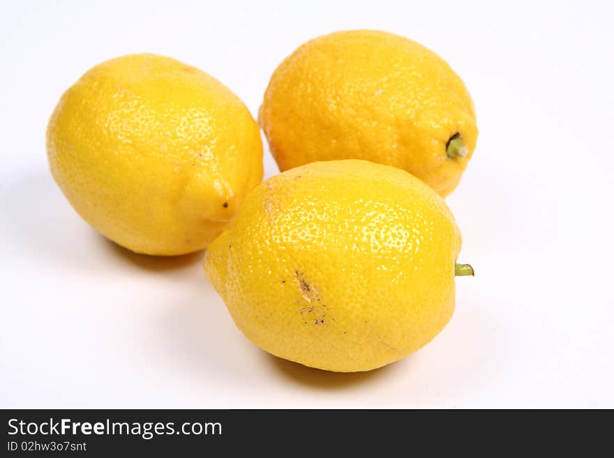 Three ripe yellow lemons on white background