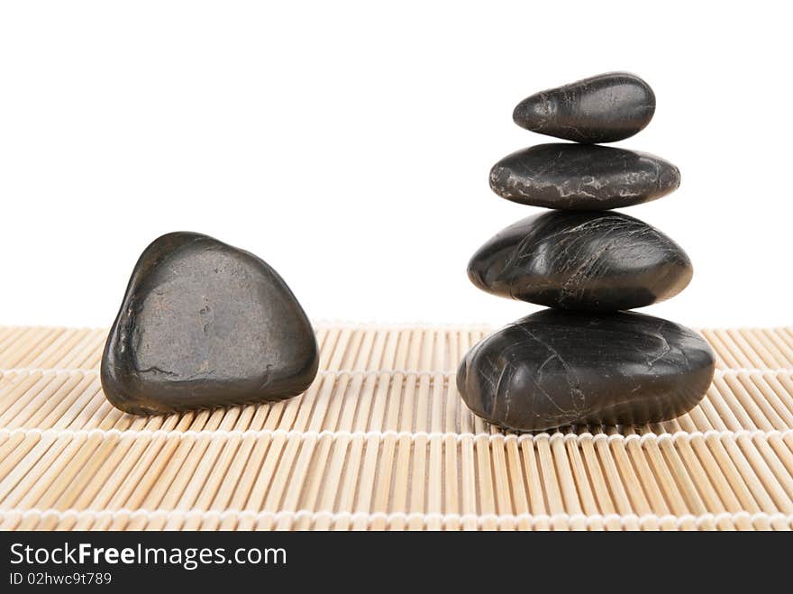 Some stones lie pyramid on mat isolated in white