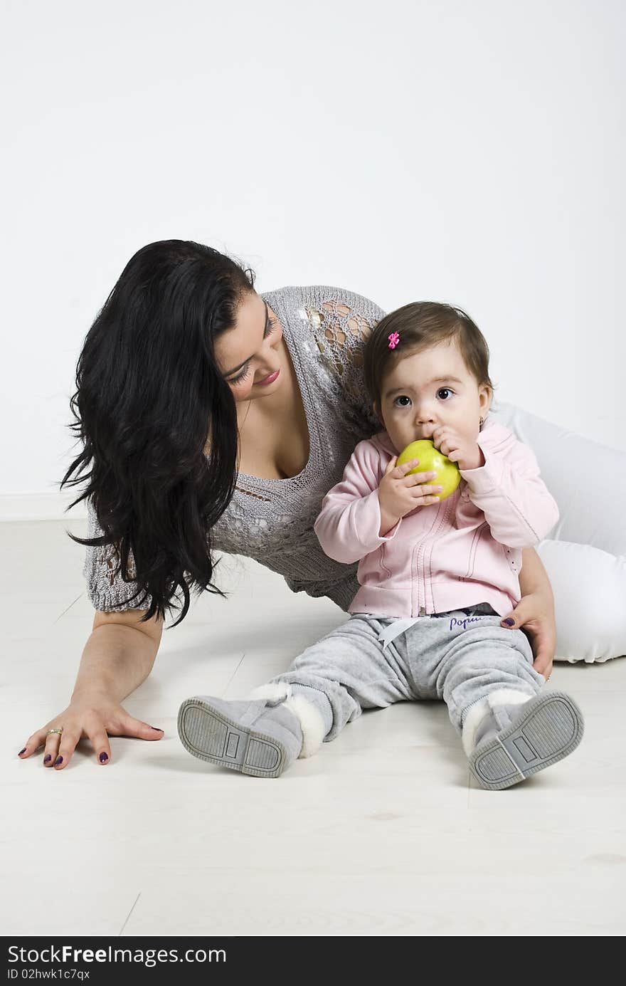 Mother sitting on floor and looking at her baby how trying to bite from an apple, check also in this collection series:. Mother sitting on floor and looking at her baby how trying to bite from an apple, check also in this collection series: