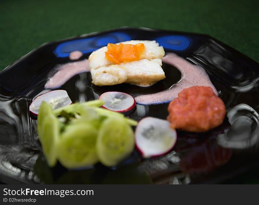 Fish plate gourmet with nice presentation on a black plate.