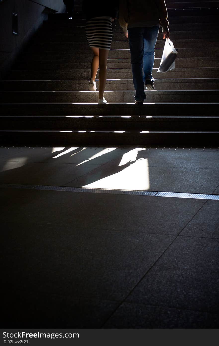 Dark subway with young people going upstairs to the sun. Stairs made of granite. Dark subway with young people going upstairs to the sun. Stairs made of granite.