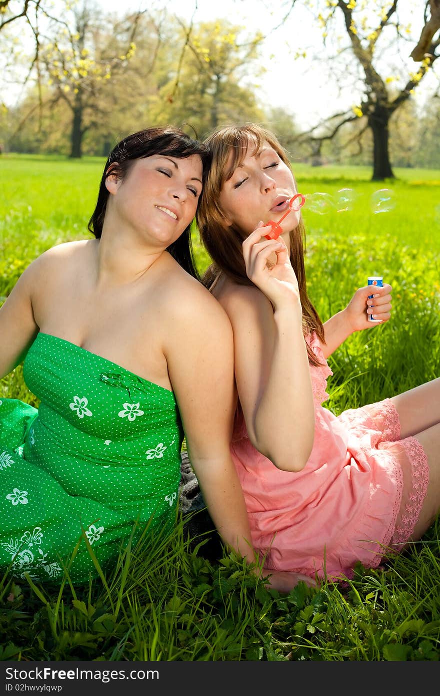 Female friends in park blowing soap bubbles. Female friends in park blowing soap bubbles