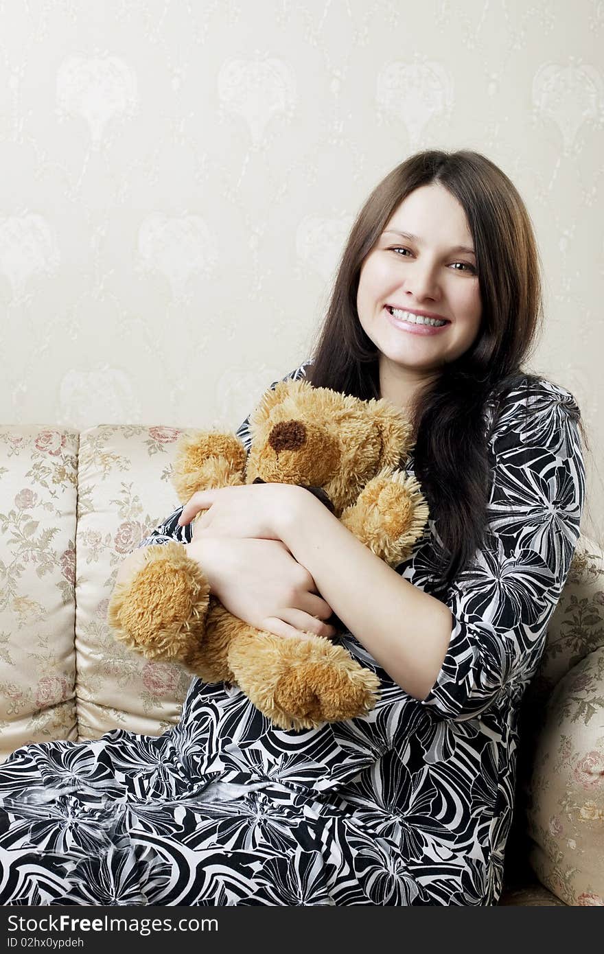 The image of a beautiful pregnant woman sitting on a vintage couch