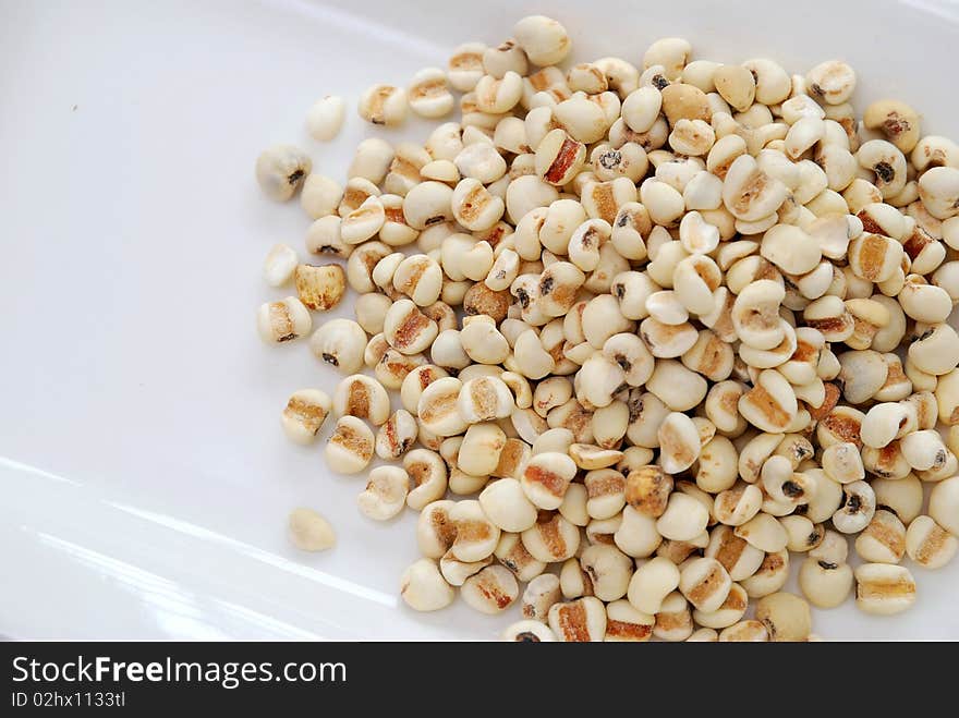 Dried barley seeds on white plate. Commonly used as a food ingredient in many Chinese cuisine and desserts. For food and beverage, and diet and nutrition concepts.