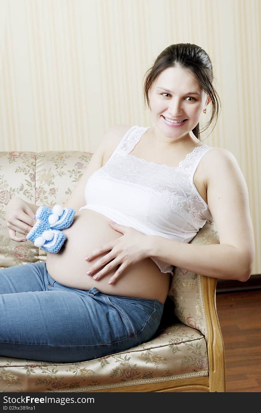 The image of a beautiful pregnant woman sitting on a vintage couch