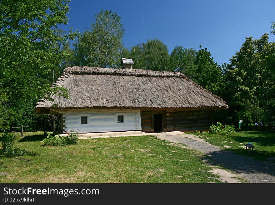 A small house with a thatched roof around a lot of green trees. A small house with a thatched roof around a lot of green trees