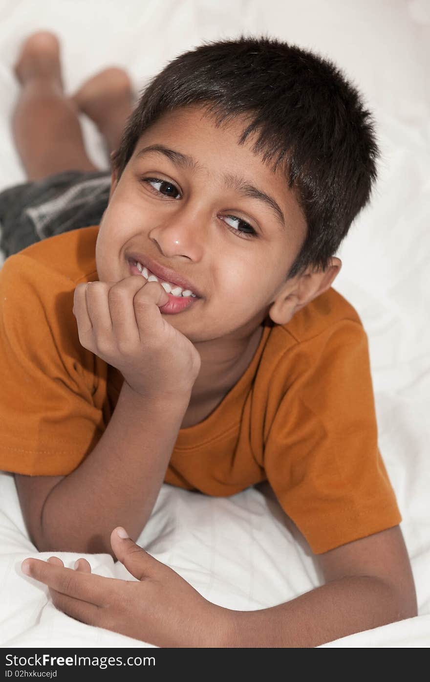 Handsome Indian kid lying happily on the bed. Handsome Indian kid lying happily on the bed