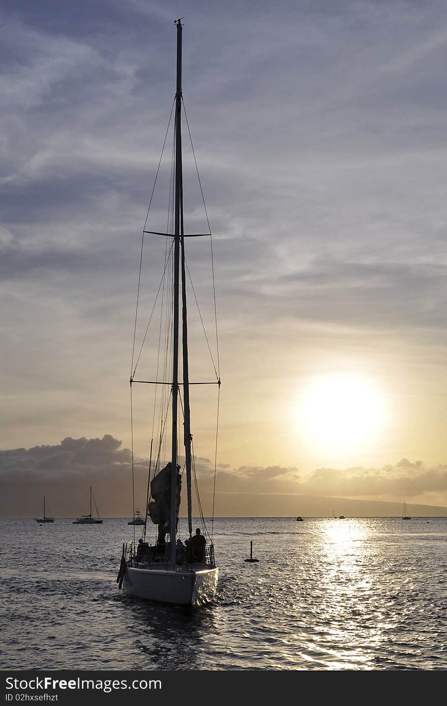 A boat is sailing back to port with a sunset background