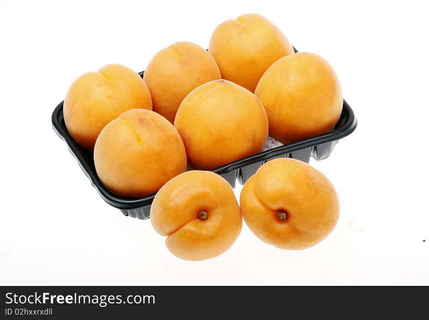 Some ripe apricot with the dark plastic box.(on white background.)