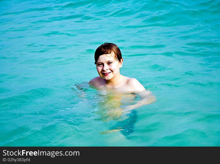 Smiling Boy Enjoys Swimming  In The Sea