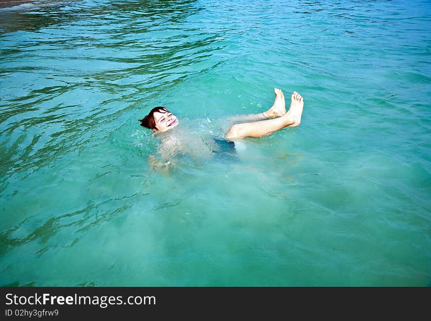 Smiling boy enjoys swimming  in the sea