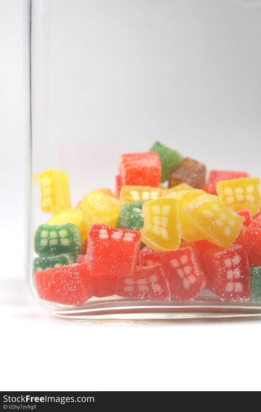 Delicious sweet candies in sugar in a glass jar. white background. copy-space