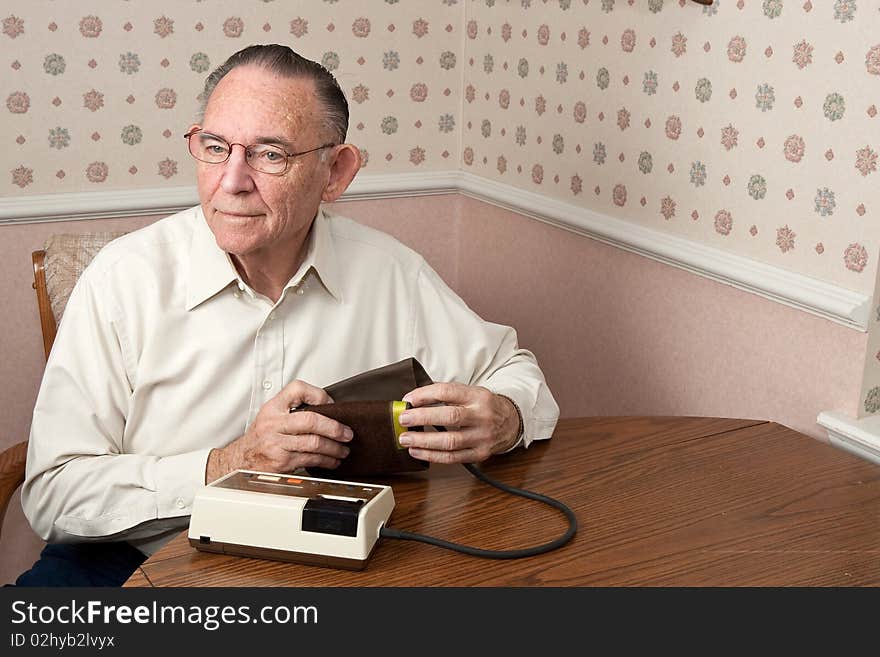 Mature man getting ready to take blood pressure in a home environment. Mature man getting ready to take blood pressure in a home environment.