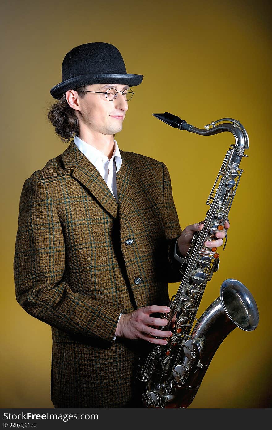 Young retro man in bowler hat with music saxophone