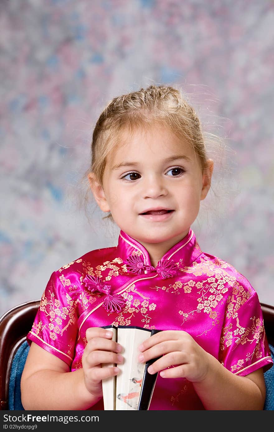 Portrait of a pretty little blond headed girl smiling and holding folding fan. Portrait of a pretty little blond headed girl smiling and holding folding fan.