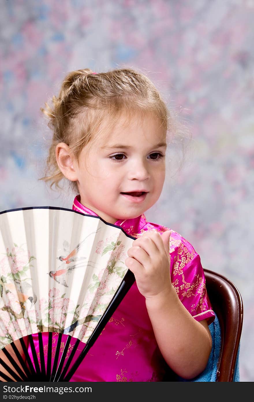 Portrait of a pretty little blond headed girl smiling and holding folding fan. Portrait of a pretty little blond headed girl smiling and holding folding fan.