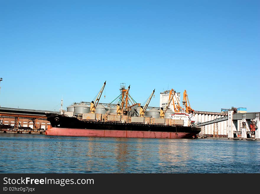 Ship receives cargo at the port, loading cranes being, but rather in the sea;. Ship receives cargo at the port, loading cranes being, but rather in the sea;