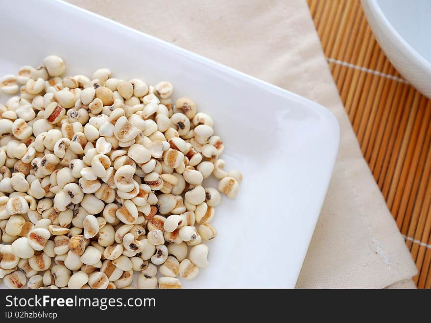 Dried barley seeds on white plate. Commonly used as a food ingredient in many Chinese cuisine and desserts. For food and beverage, and diet and nutrition concepts.