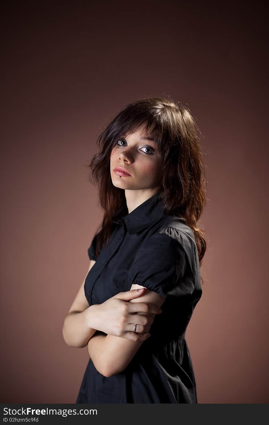 A young girl in a black dress on a brown background. A young girl in a black dress on a brown background