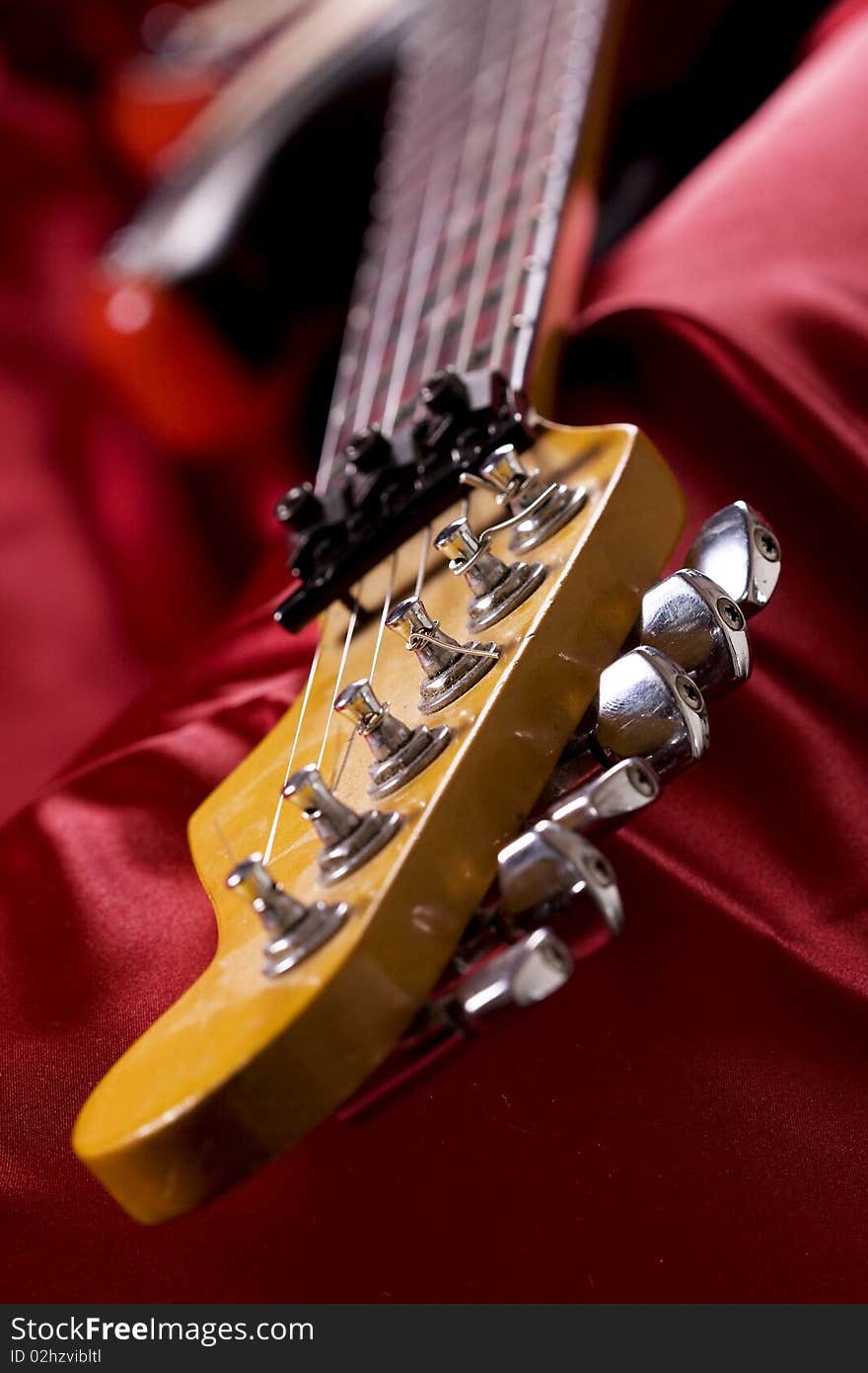 Close-up on an electric guitar on red satin background. Close-up on an electric guitar on red satin background