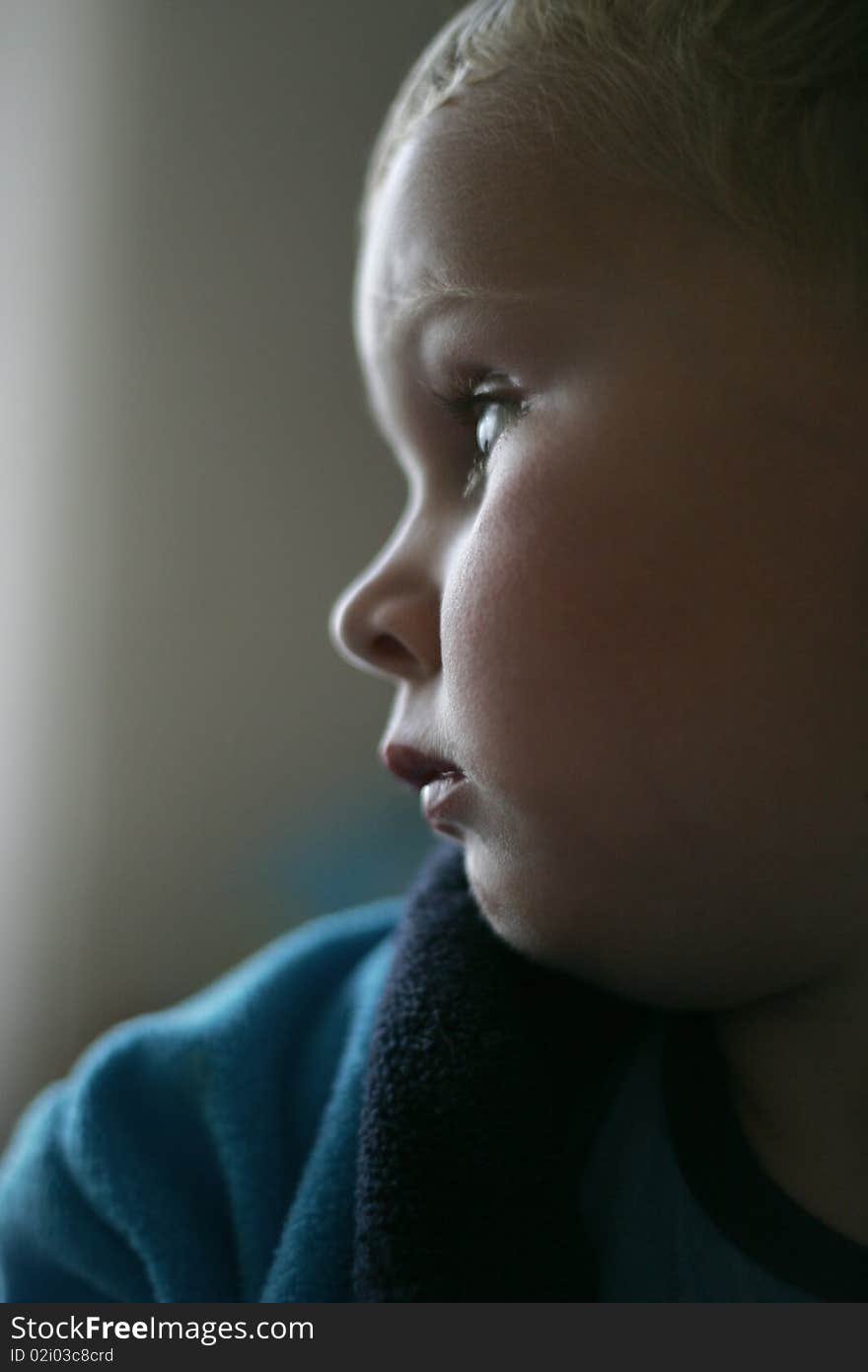 Three year old boy in unhappy mood, backlit