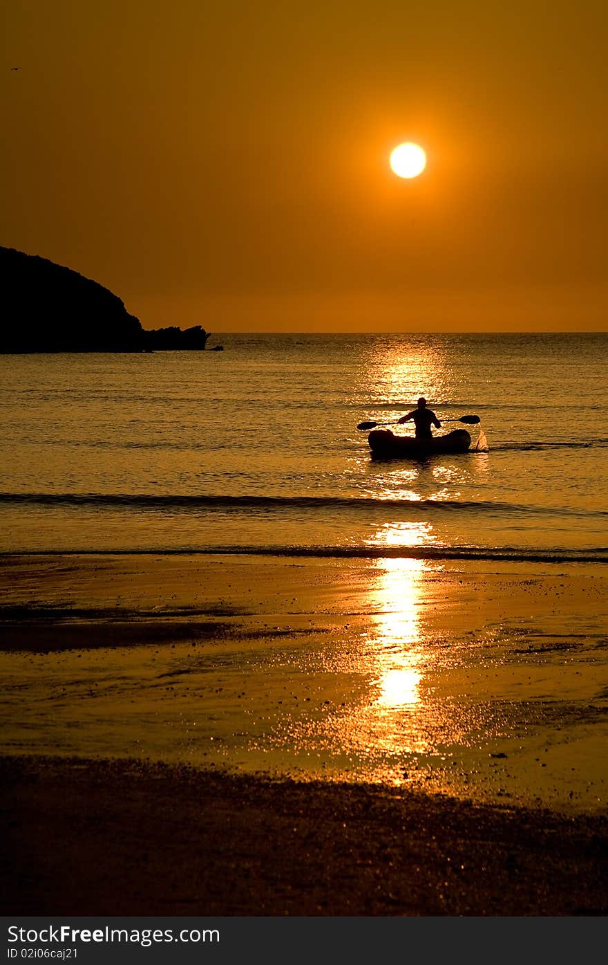 Image of a kayak in the ocean at sunset