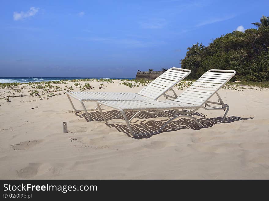 Profile view of a pair of beach lounge chairs on one of Barbados beautiful beaches. Profile view of a pair of beach lounge chairs on one of Barbados beautiful beaches.